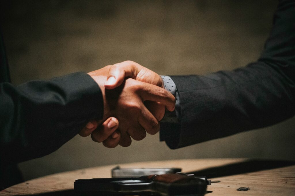 Close up shot of 2 suited hands shaking each other in a clandestine setting | Arkestro