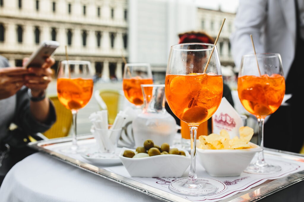 four glasses of Aperol Spritz cocktail on a white table | Celonis launches new Process Collaboration Agent for improved decision-making