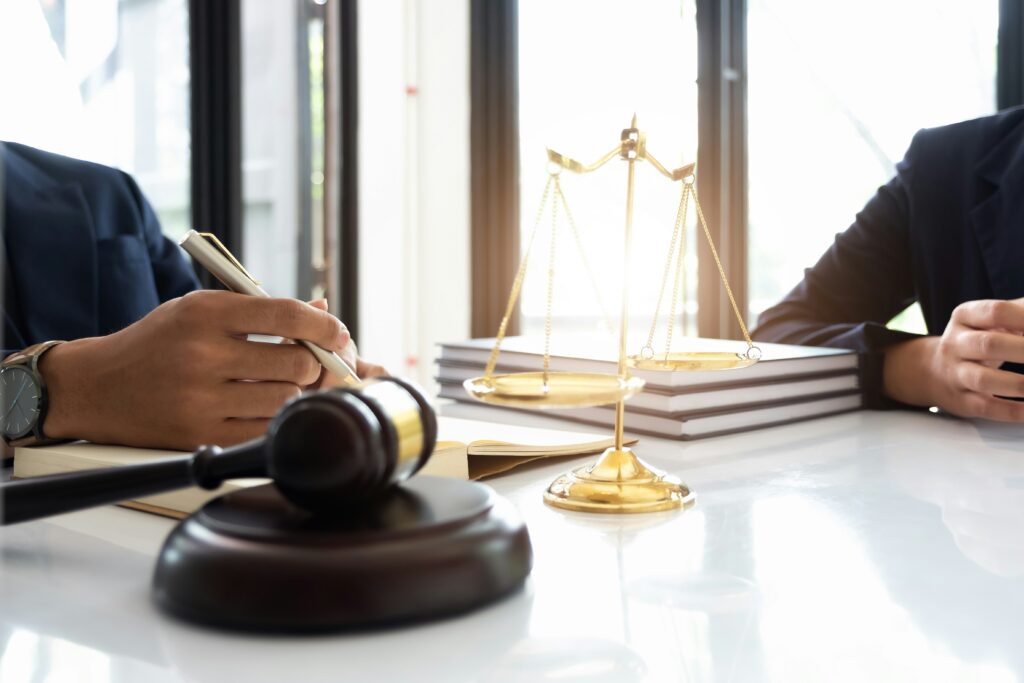 two people dressed in office attire sitting at a table with scales and justice in front of them | How Oracle Cloud ERP and Accelalpha Extend meet law firms’ needs