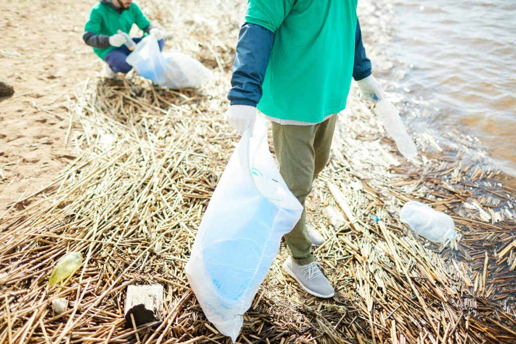 two people cleaning up a river bank