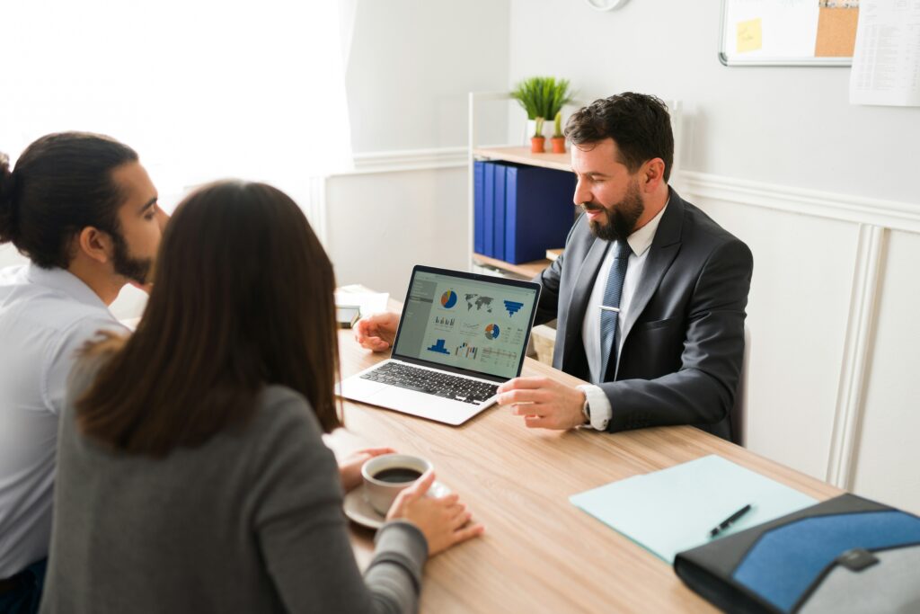 three people in office outfits talking near a computer