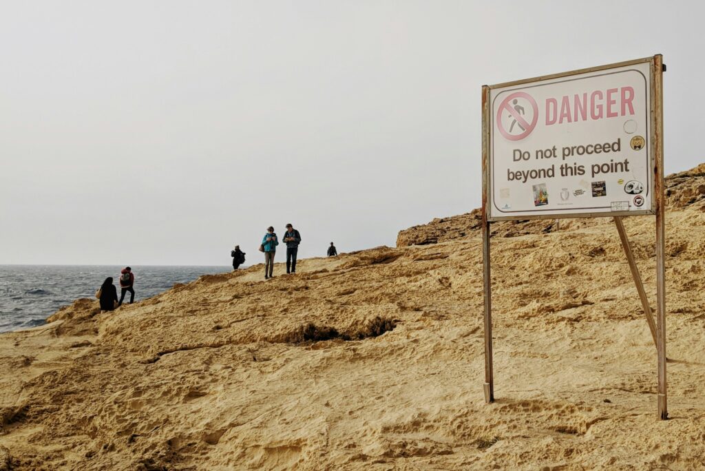 a danger sign displayed on a sandy beach