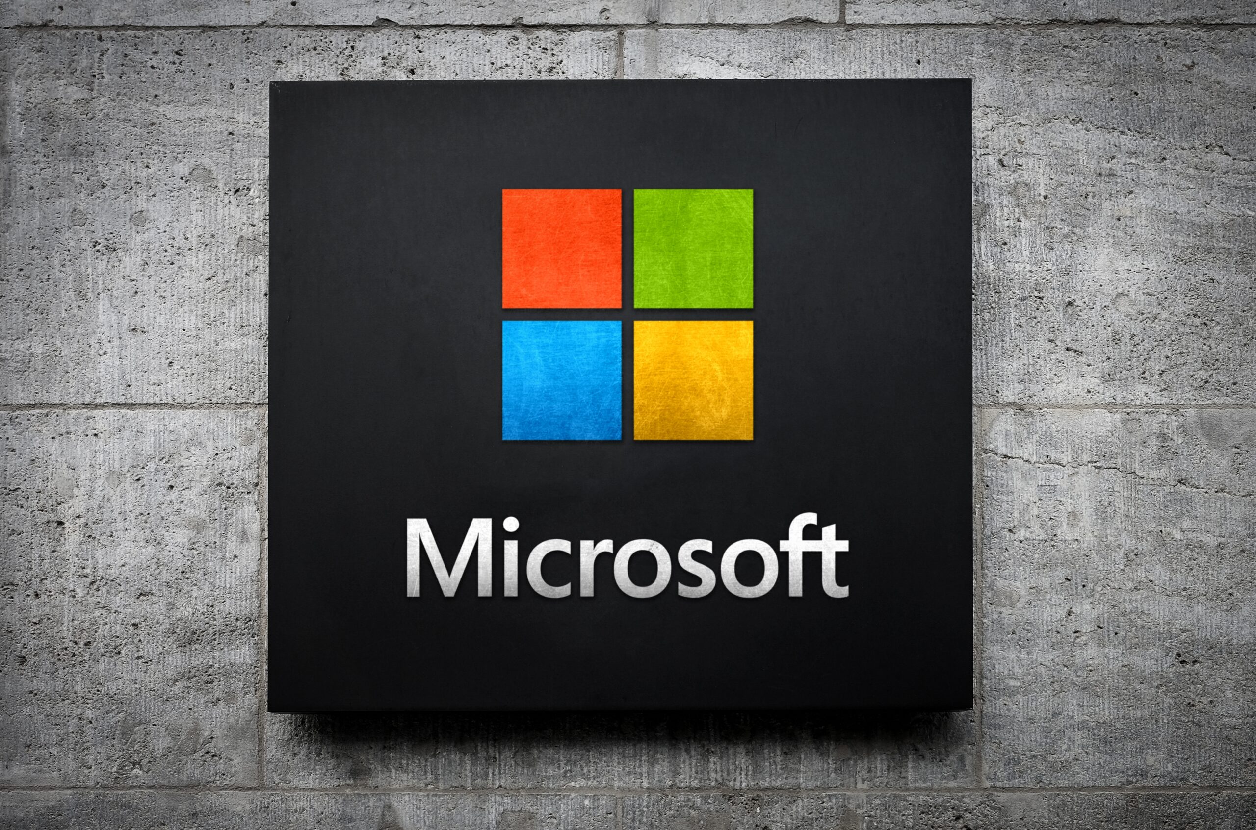 Microsoft logo displayed on a dark sign mounted on a concrete wall