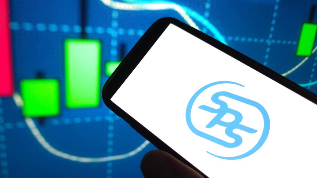 SPS Commerce logo displayed on smartphone screen with financial and supply chain analytics background.