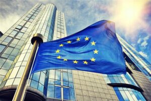 European Union flag in front of modern glass office buildings symbolizing cloud sovereignty and digital regulation in Europe.