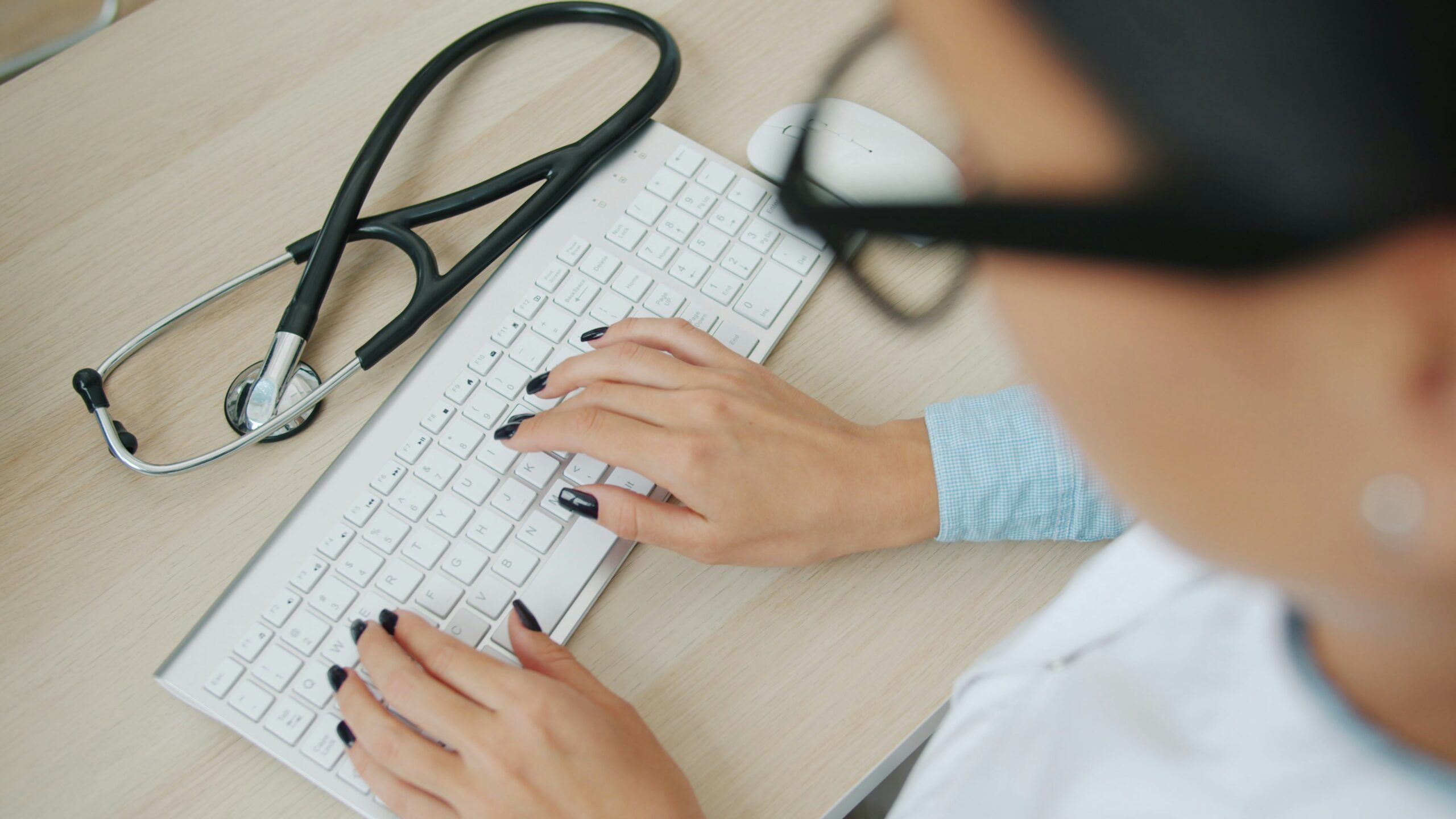 High angle shot of doctor working with keyboard typing.