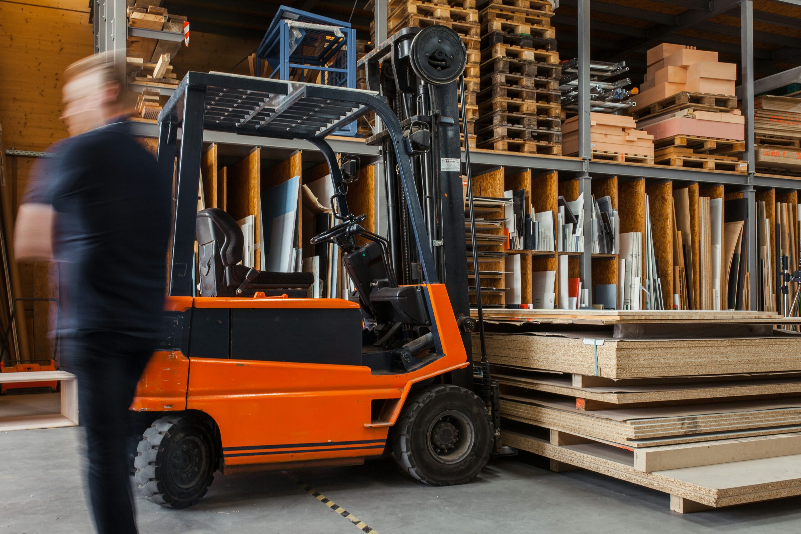 Worker with a forklift in a large carpentry workshop with many timbers in the background._SAP Ariba AI procurement