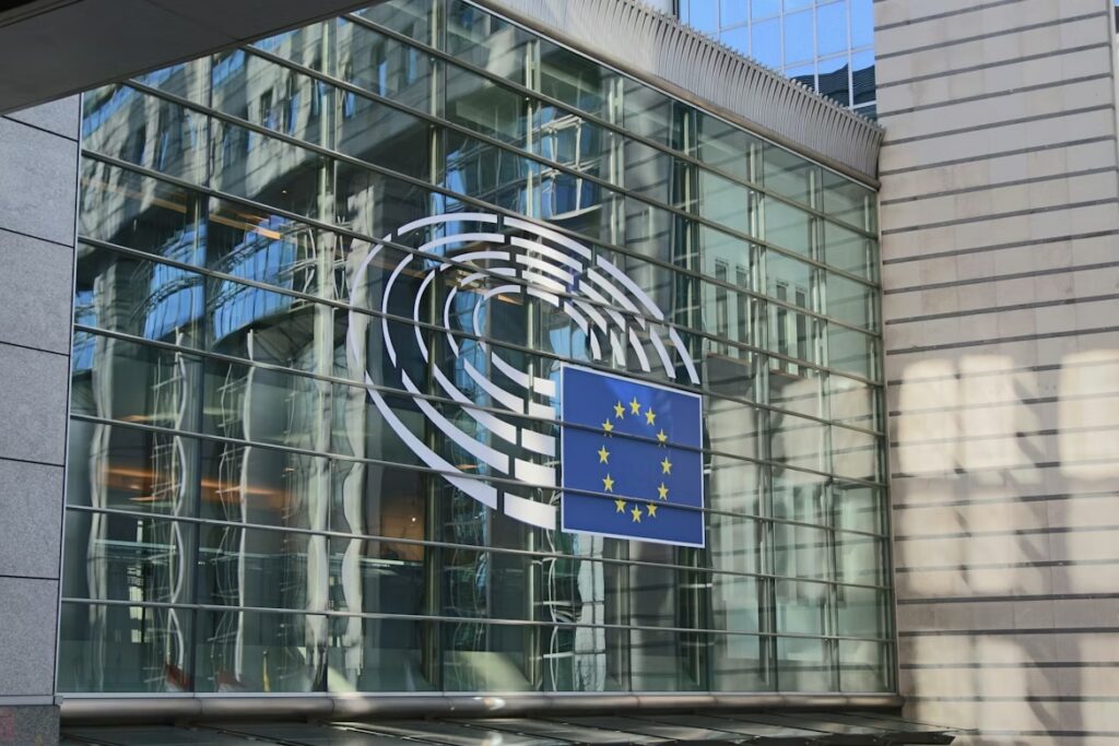 EU flag displayed on the glass exterior of the European Parliament building, representing ERP governance questions around the EU AI Act delay.