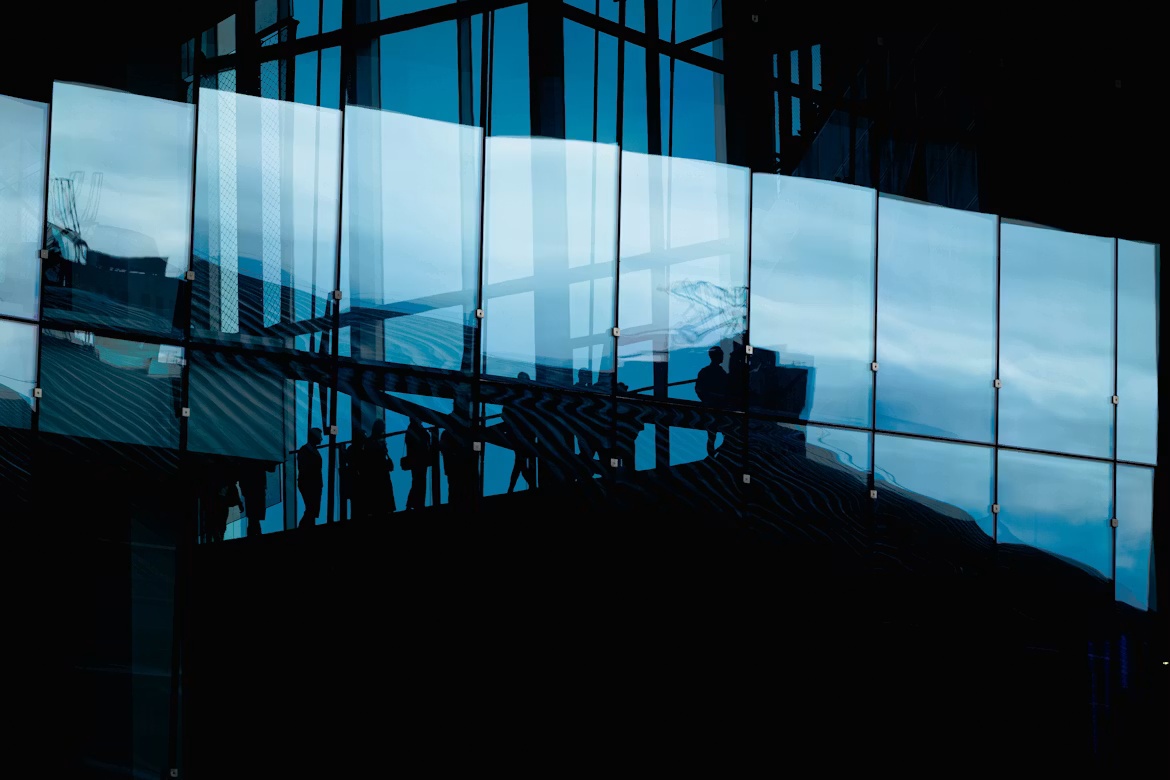 Business silhouettes behind blue glass panels, illustrating AI pricing, billing, and revenue recognition across enterprise finance systems.