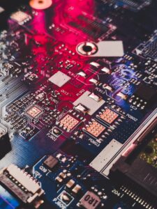 Red and blue illuminated circuit board with labeled components representing the interconnected mid-market ERP delivery network Accenture is building through COMWARE and McCoy