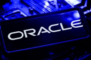 Oracle logo displayed on a smartphone screen resting on a blue-lit computer circuit board, illustrating Oracle Q1 FY27 results and its cloud infrastructure buildout