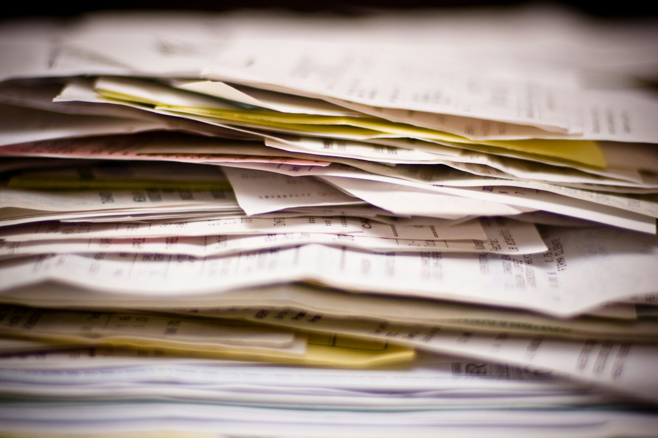 Stack of paper documents and files illustrating manual contract management, fragmented records, and paperwork-heavy procurement processes.
